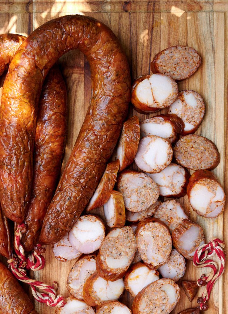 Andouille sausage link on a wooden cutting board with sliced andouille pieces showing the smoky Cajun sausage used in Lucky Cajun Black Label seasoned andouille boudin cornbread Thanksgiving dressing