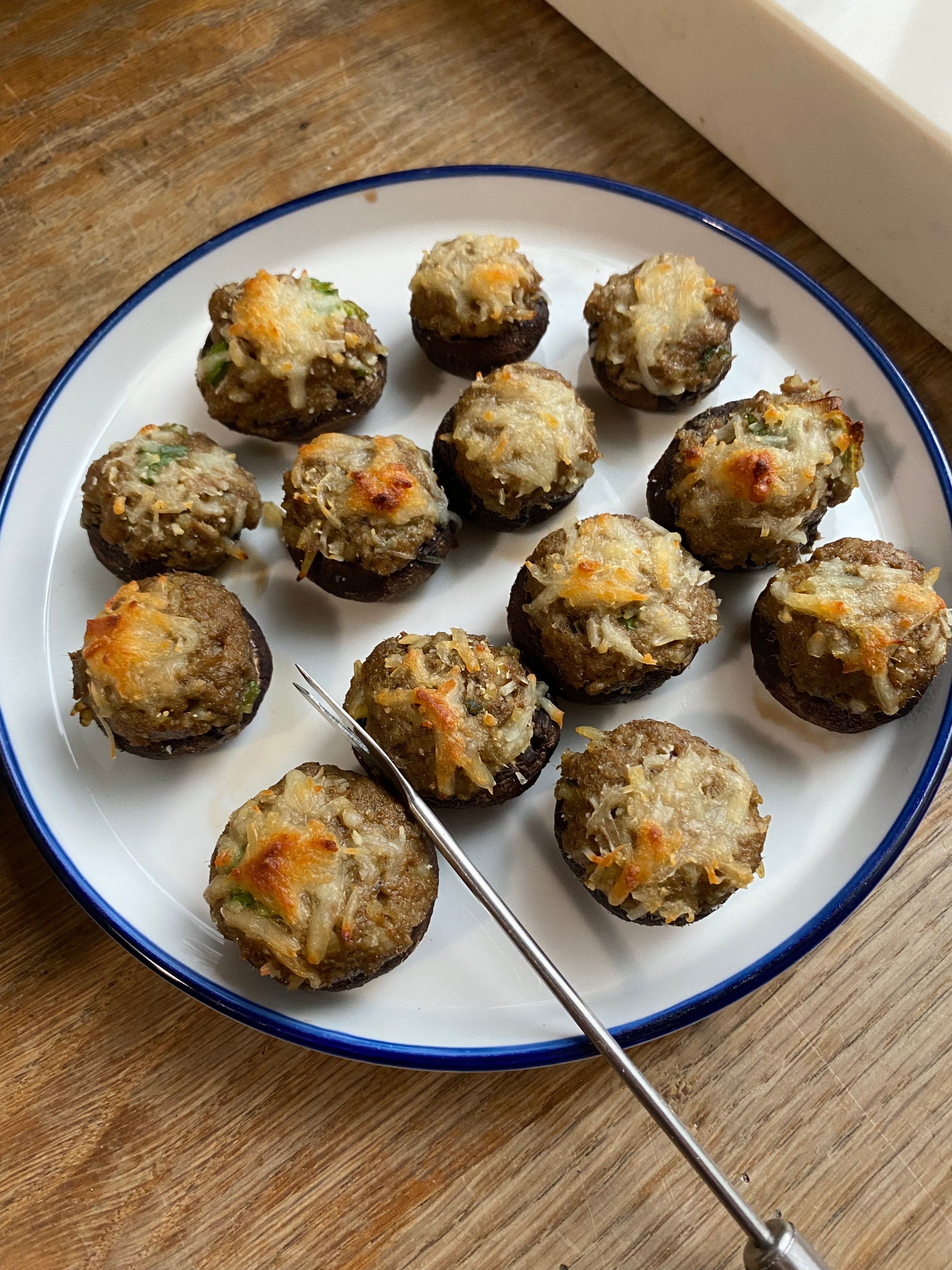 Plate of boudin stuffed mushrooms topped with toasted melted Asiago cheese, served with dill horseradish sauce — a one-bite Cajun appetizer made with Lucky Cajun Black Label.