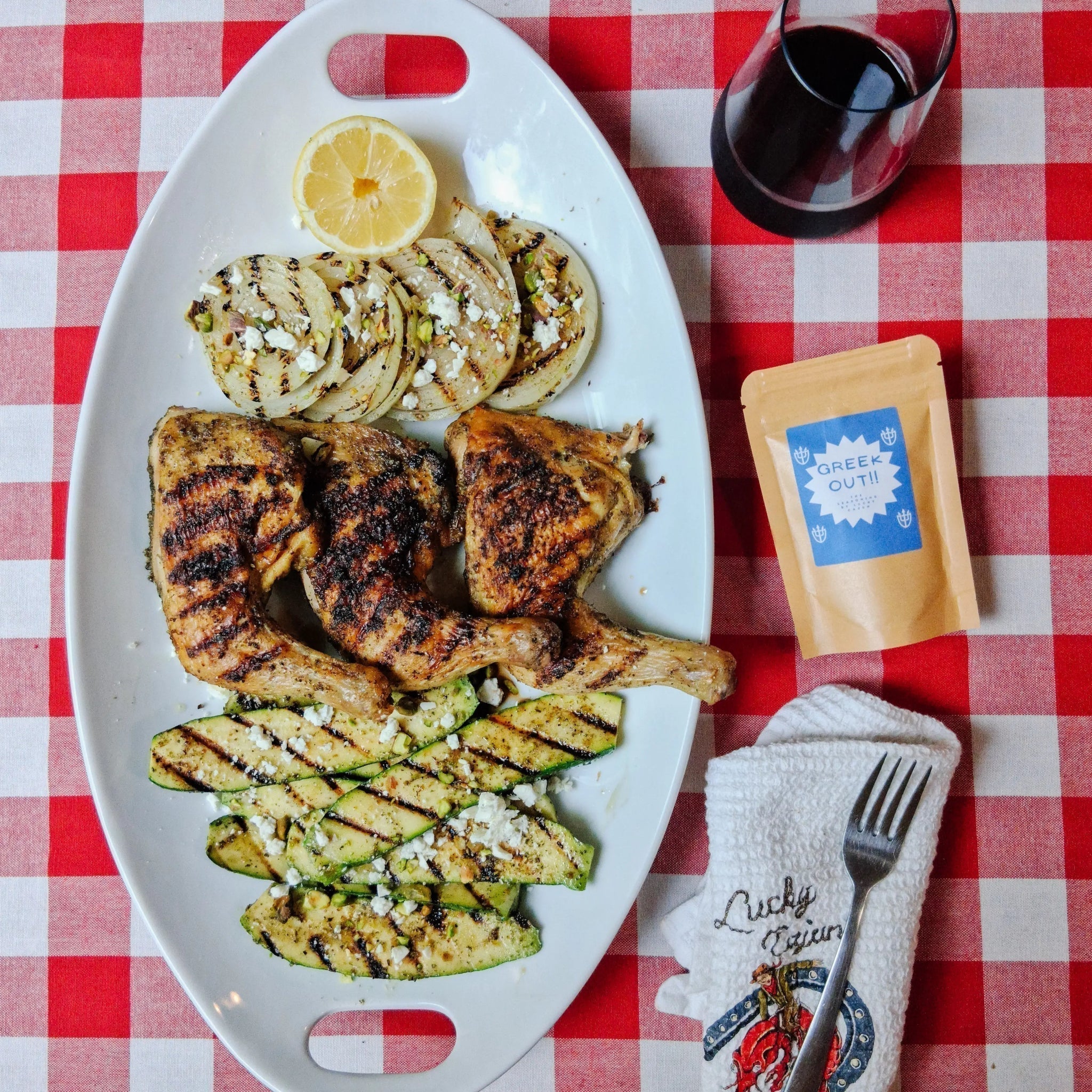 Greek grilled chicken leg quarters with charred lemon balsamic glazed zucchini feta and pistachios seasoned with fresh ground Lucky Cajun Greek Out