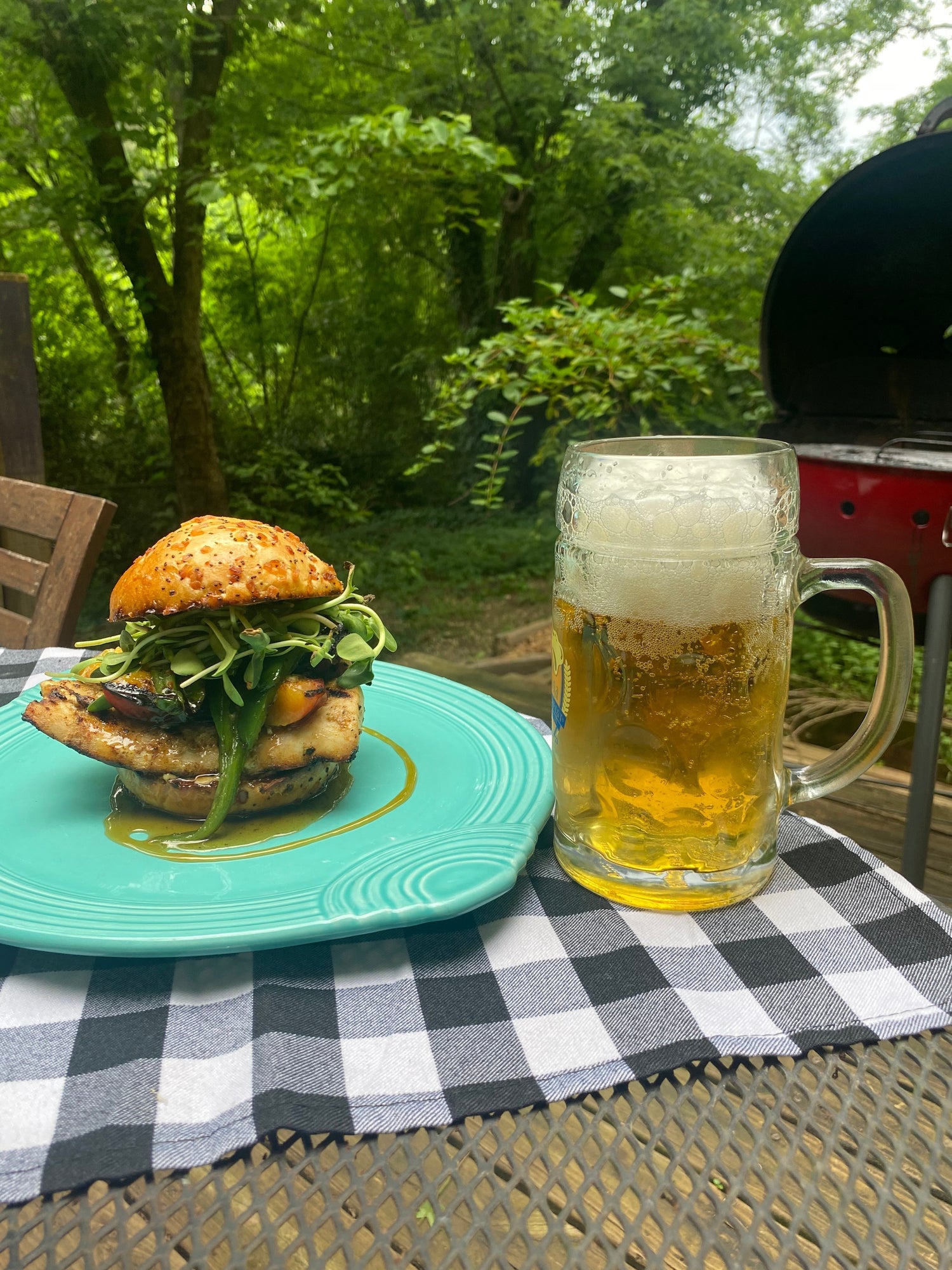 Grilled cobia sandwich with sweet peaches, jalapeños, goat cheese and honey on a toasted bun, served with a cold beer outside by the grill — seasoned with Lucky Cajun.