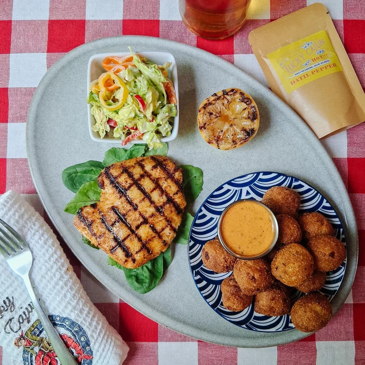 Grilled grouper seasoned with Lucky Cajun Fiery Datil served with hush puppies slaw and grilled lemon showing the seared crust from grilling fish over high heat