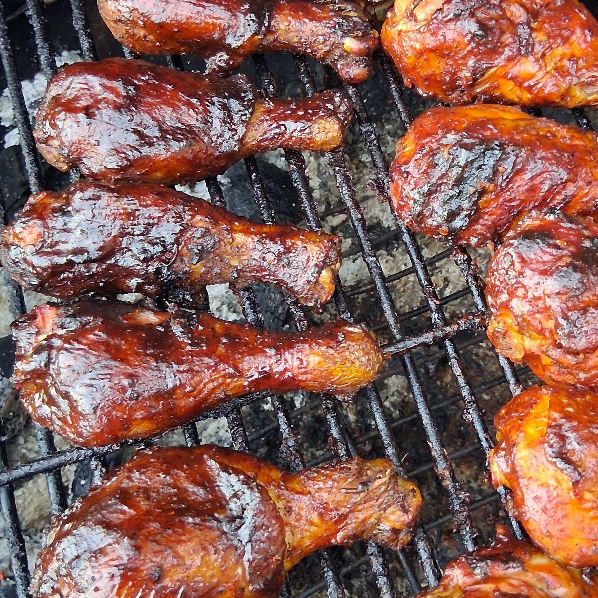 BBQ chicken legs on the grill brushed with peach BBQ sauce made with Lucky Cajun Black Beard's Smoke fresh ground sugar free Cajun seasoning showing the best Cajun seasoning for chicken on the grill