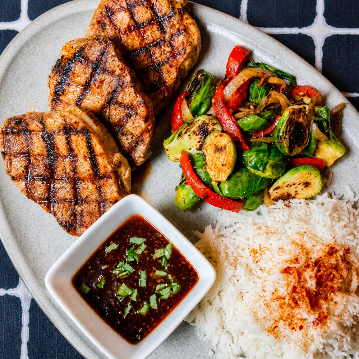 Grilled pork chops seasoned with Bulgasari Cajun-Korean fusion spice, served with stir-fried Brussels sprouts, steamed rice, and a sesame soy glaze. Small-batch umami seasoning with a Born On Date.