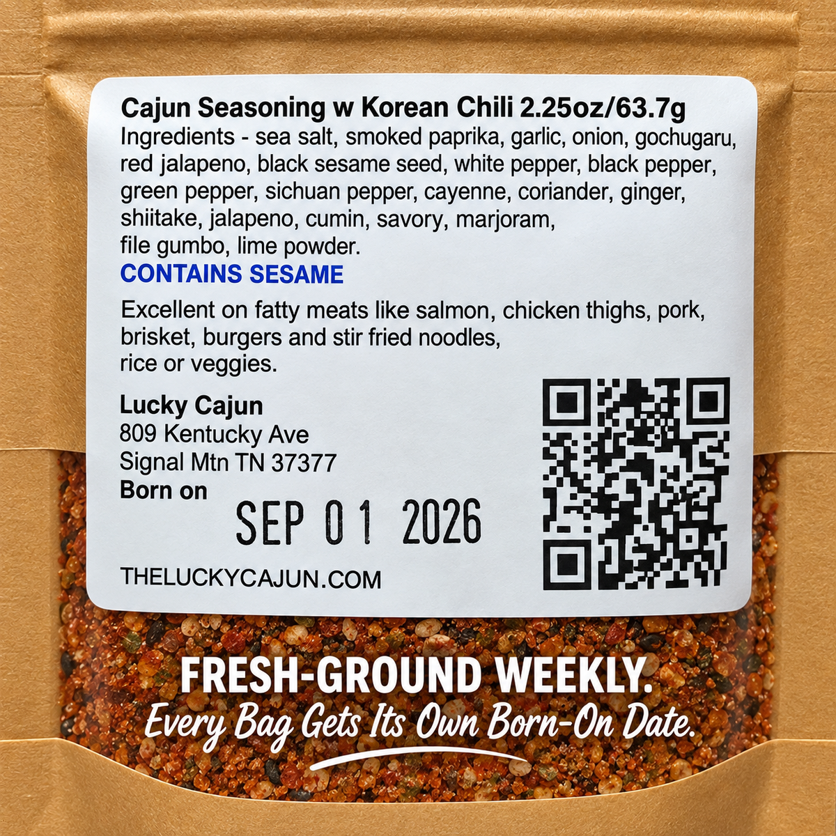 Close-up of a spice seasoning packet label showing Cajun Seasoning w/ Korean Chili, with ingredients listed on a white sticker over a brown kraft pouch and visible ground spices through the clear lower section.