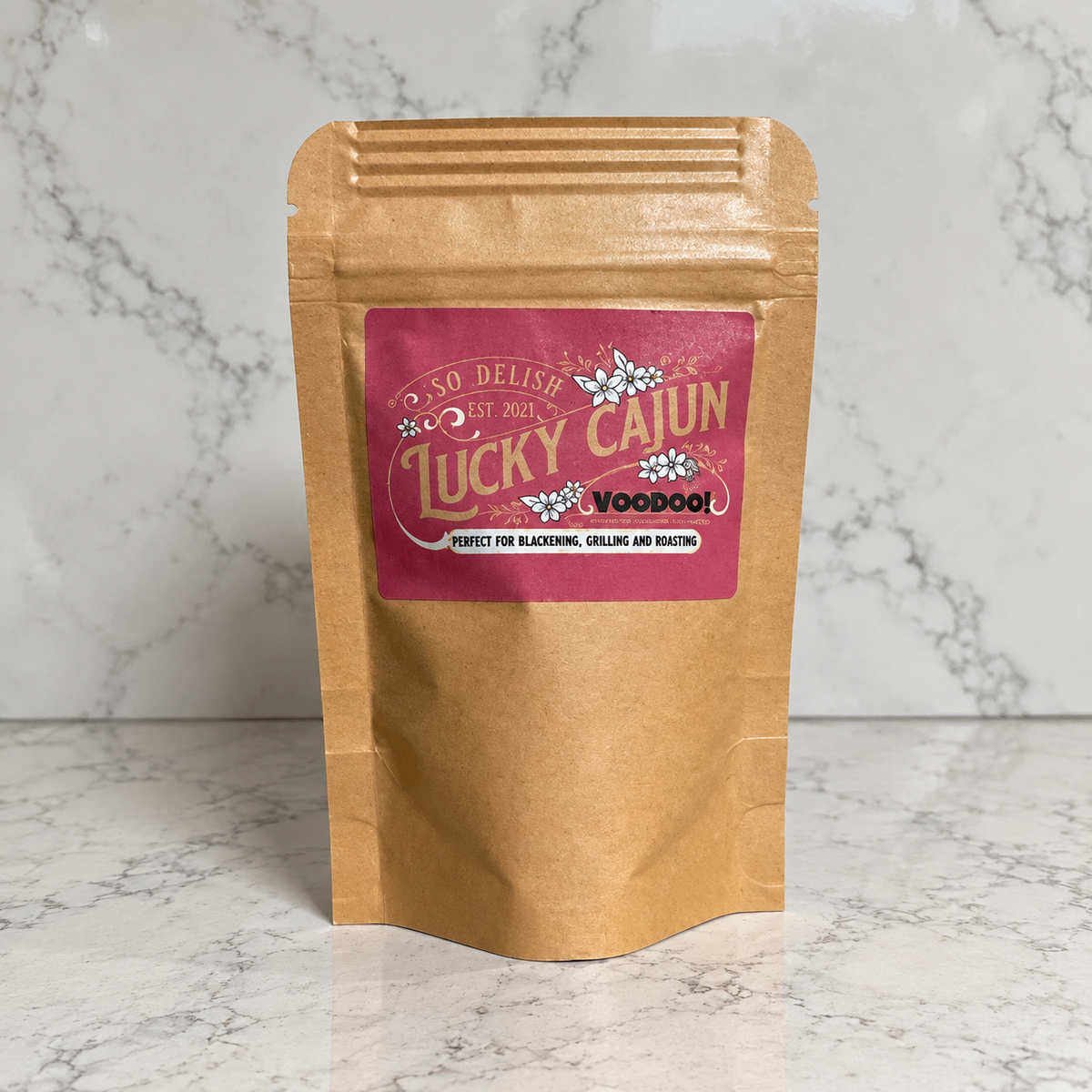A brown kraft paper stand-up pouch of Lucky Cajun VooDoo! seasoning, set against a white marble background.