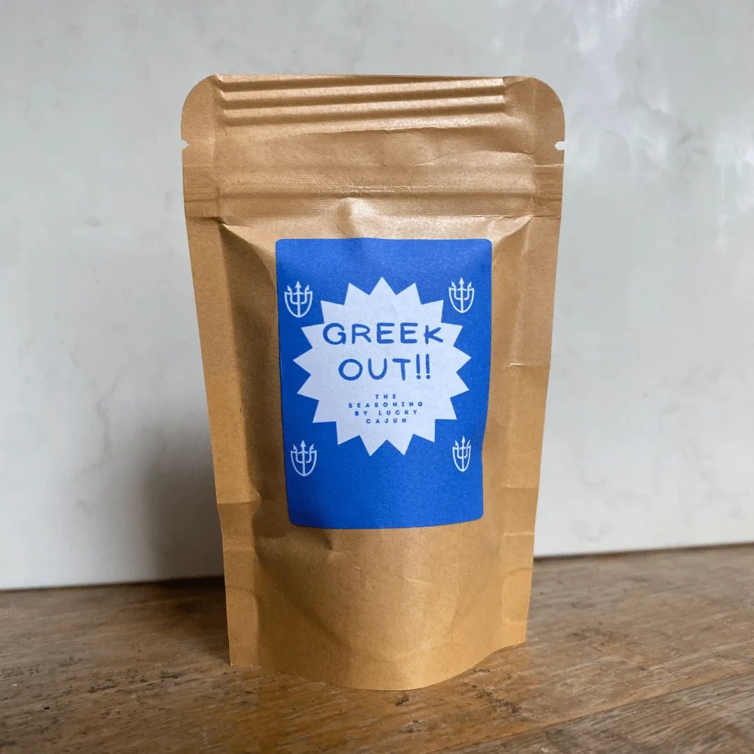 Lucky Cajun Greek Out Mediterranean seasoning pouch on a table next to a white background. Small-batch, fresh-ground Greek herbs and lemon blend with a Born On Date.