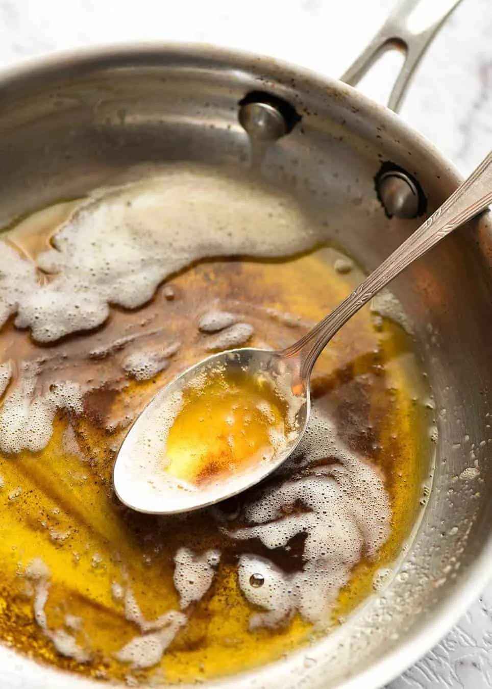 Pan with browned butter and a spoon showing the golden amber color and nutty aroma of properly made brown butter sauce