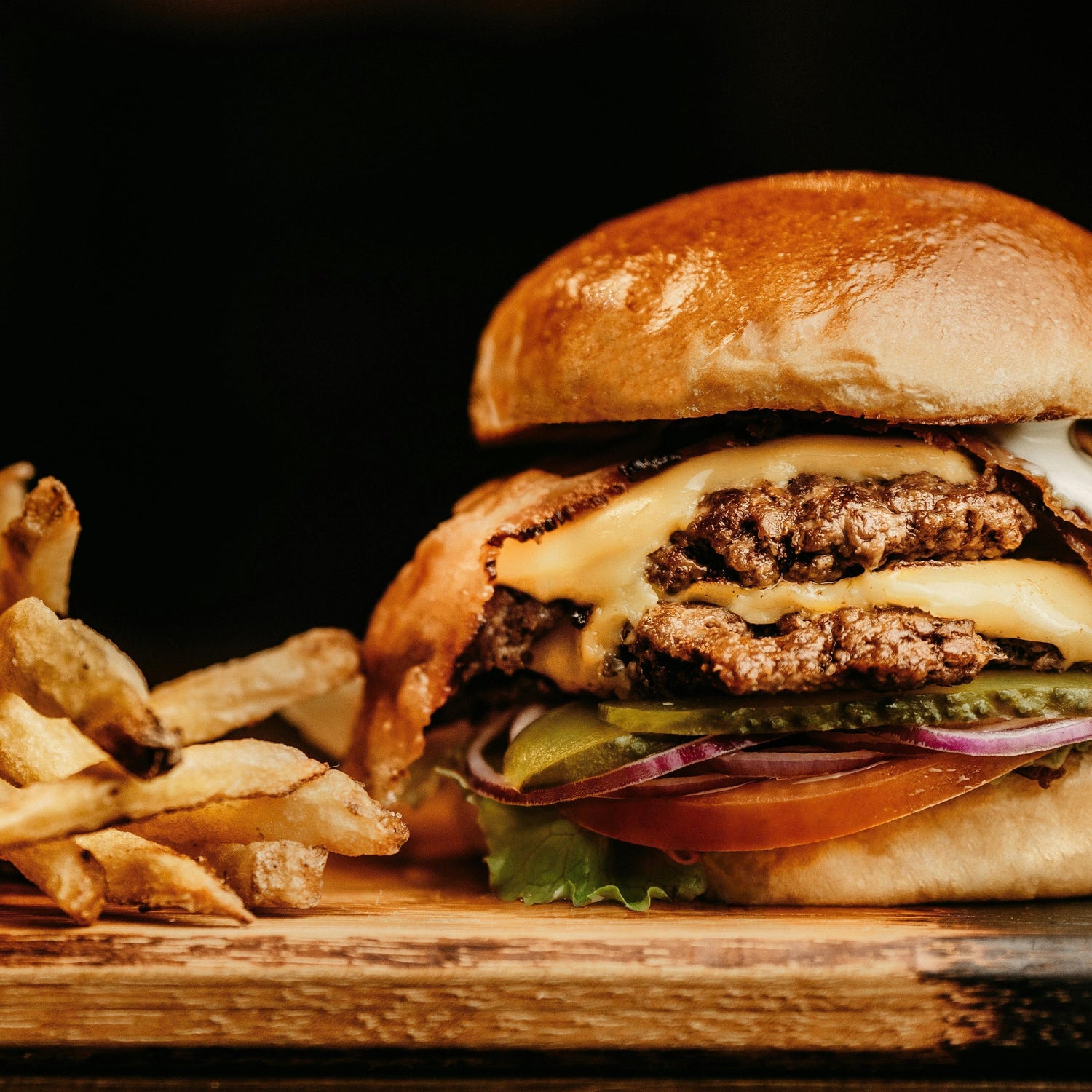 Close up of a bacon cheeseburger with melted cheese on a beef patty showing the crust built with Lucky Cajun fresh ground sugar free Cajun seasoning and the layered toppings that make a great burger
