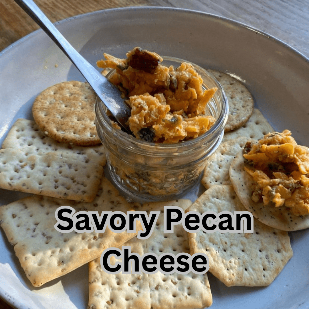 Savory pecan cheese spread with Lucky Cajun Black Label in a small glass jar on a plate with a spreader and crackers showing the creamy Cajun seasoned cheddar and roasted pecan appetizer