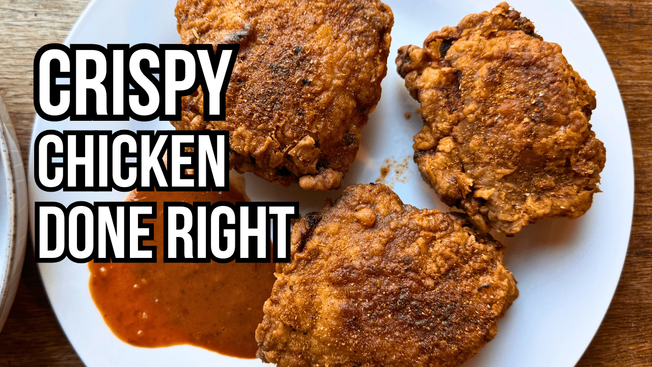 Hand holding a crispy golden fried chicken thigh seasoned all the way through with Lucky Cajun Black Label showing the perfect crust from a proper buttermilk and pickle brine method