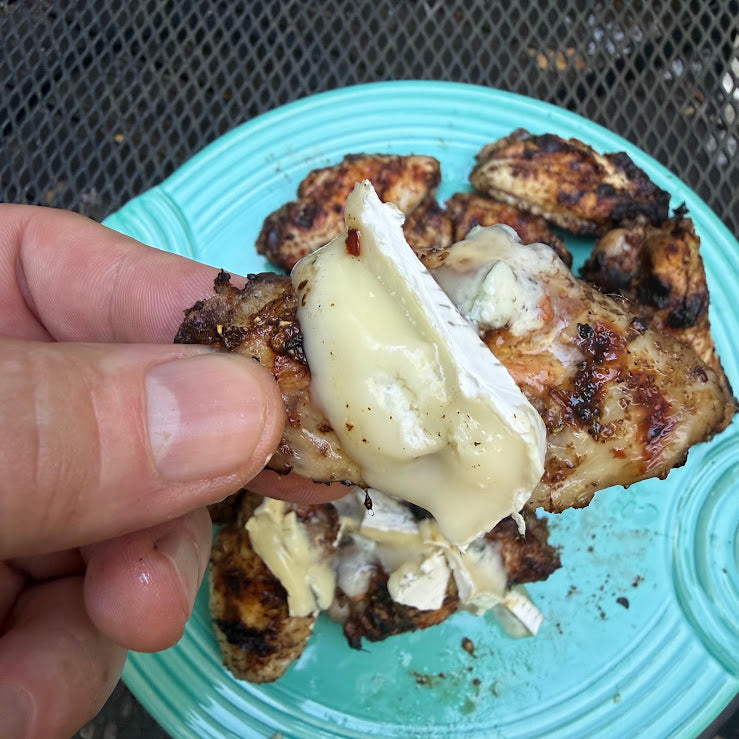 Balsamic italian grilled wings with blue brie over plate of wings on patio table
