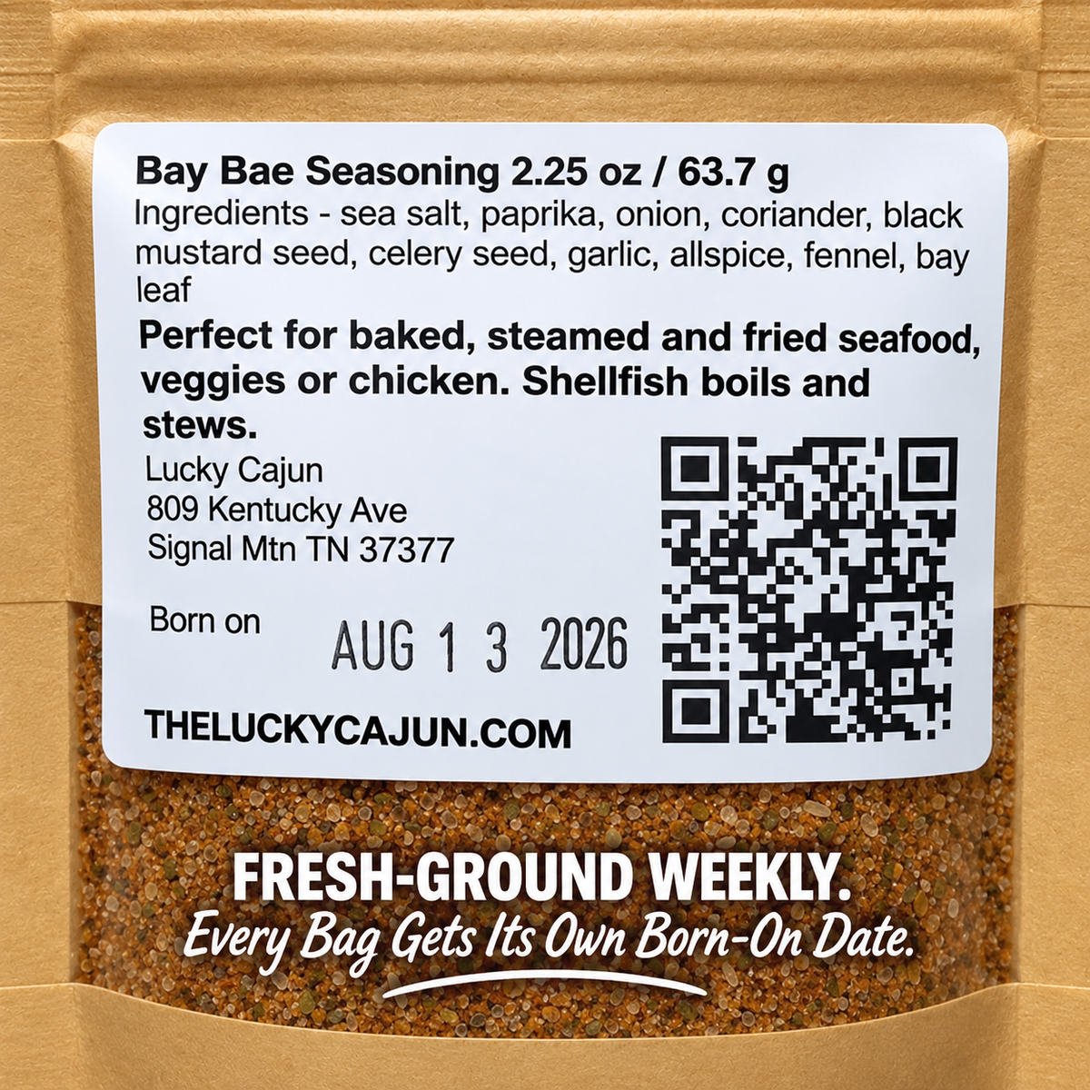 A close-up of a brown kraft paper bag of Bay Bae Seasoning, showing the front label with product details, ingredients, a QR code, and the Lucky Cajun brand name.