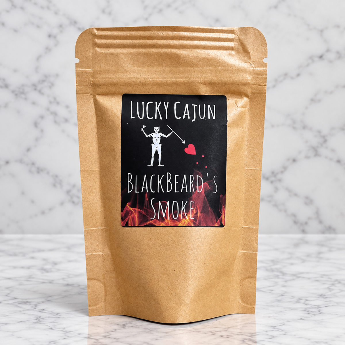 A kraft paper stand-up pouch labeled 'Lucky Cajun Blackbeard's Smoke' stands on a white marble surface against a white marble background.