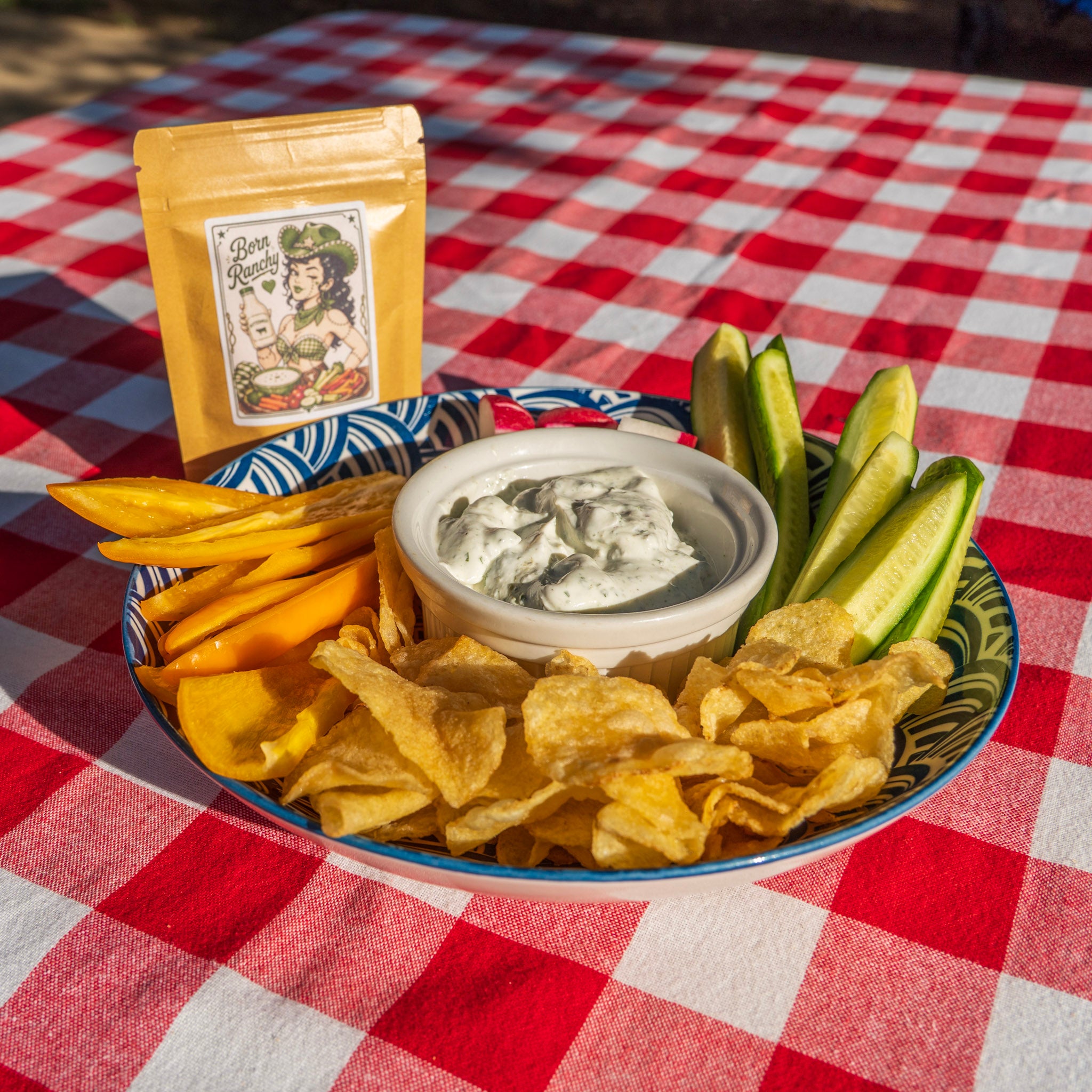 Born Ranchy fresh ground ranch seasoning mixed into sour cream dip served with cucumbers peppers chips and radishes showing the real herbs in the blend