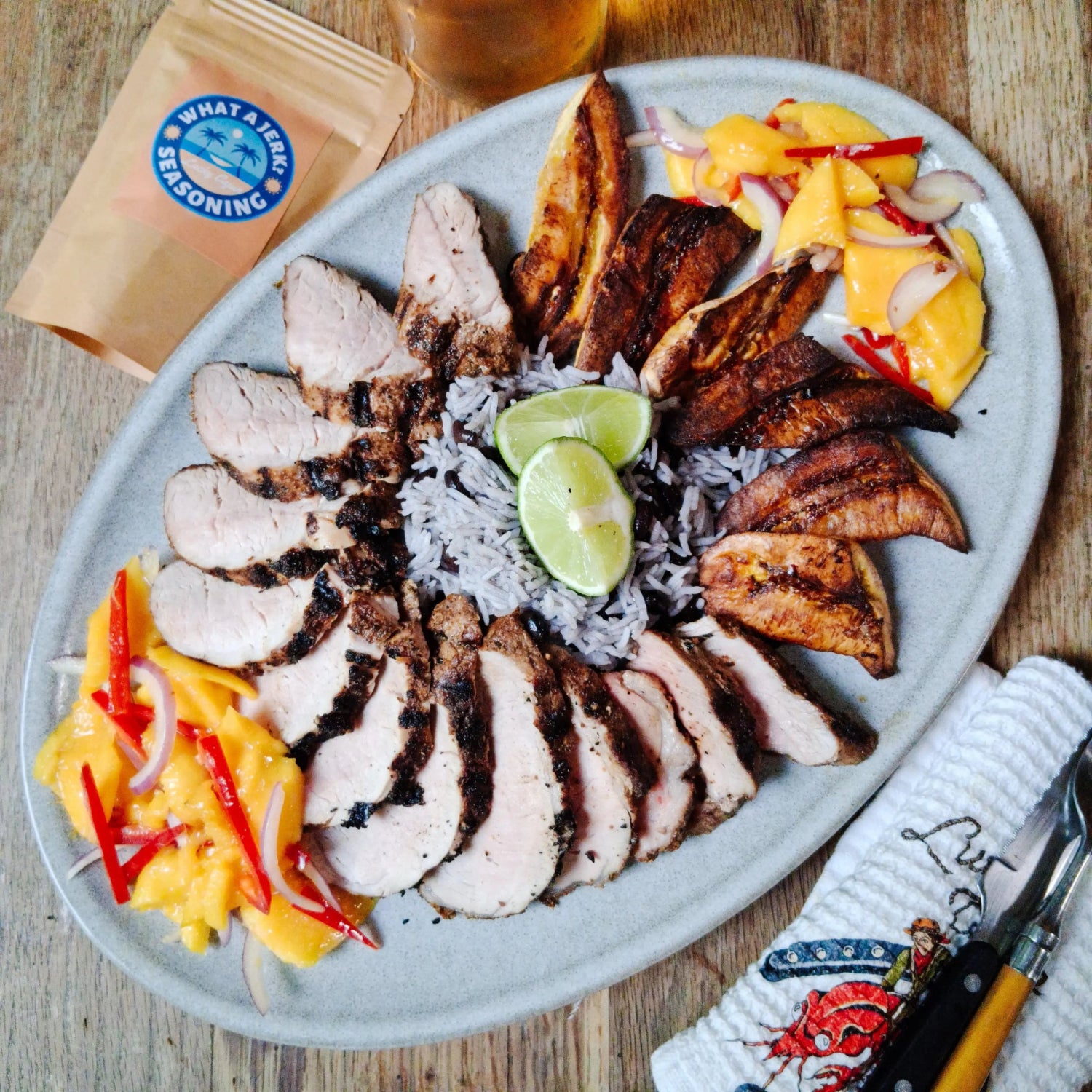 Sliced jerk chicken with rice, lime, sweet plantains, and mango red pepper salad seasoned with What A Jerk? sugar-free seasoning.