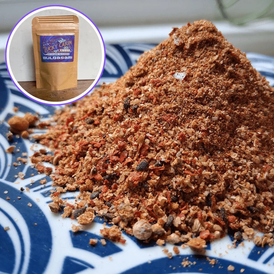 A close-up texture shot of Bulgasari Cajun-Korean fusion spice on a plate. Visible black sesame seeds, Korean chili flakes, and shiitake mushroom powder. Fresh-ground, small-batch seasoning with no MSG.