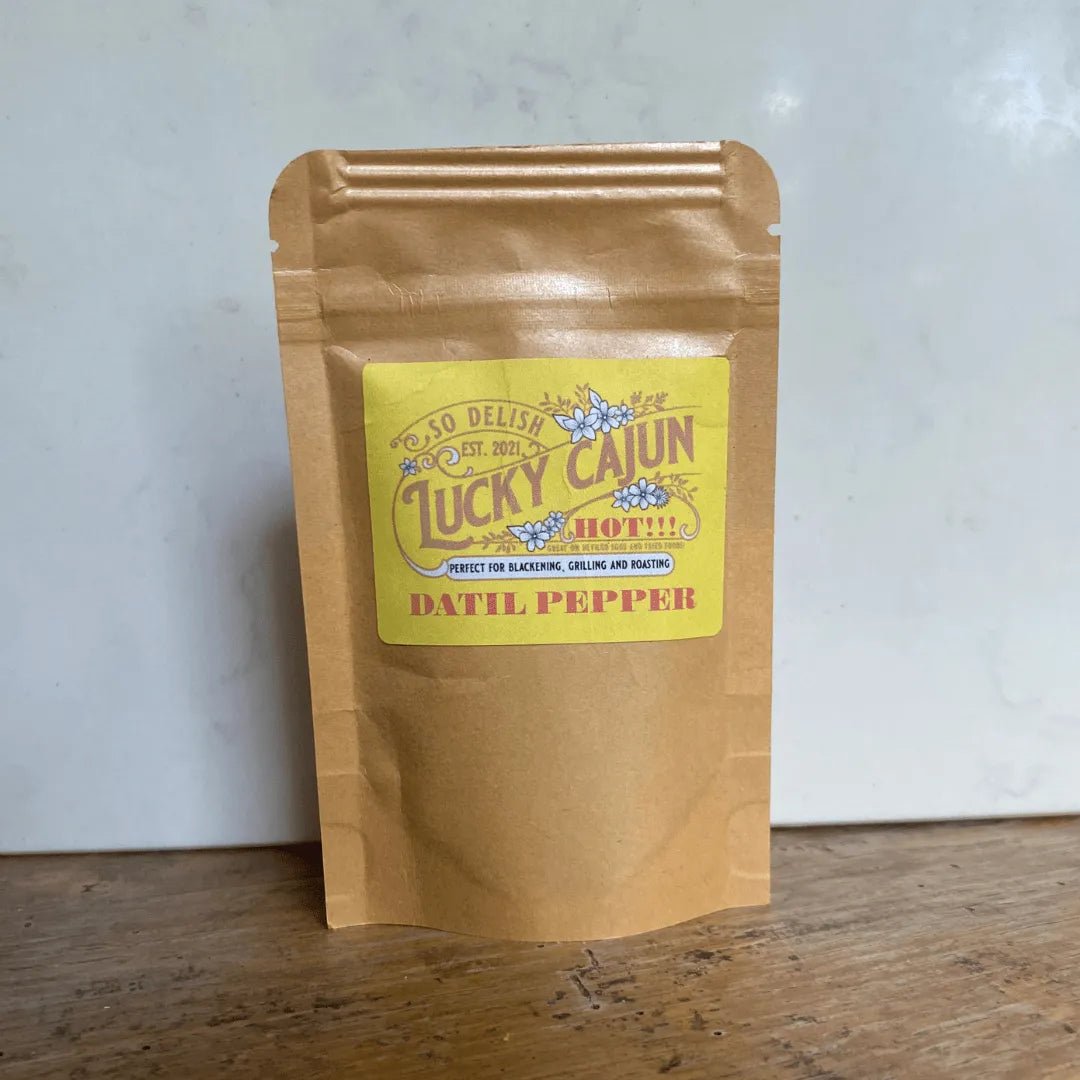 Lucky Cajun Fiery Datil seasoning pouch on a rustic wooden table with a clean white background. Small-batch tropical Cajun rub featuring a Born On Date and fresh-ground spices.