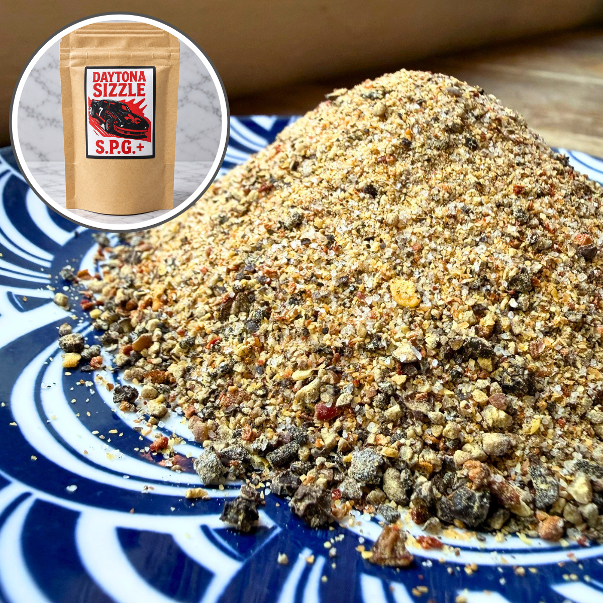 A close-up of a mound of coarse spice blend on a blue-and-white patterned plate, with a circular inset showing a kraft pouch labeled Daytona Sizzle S.P.